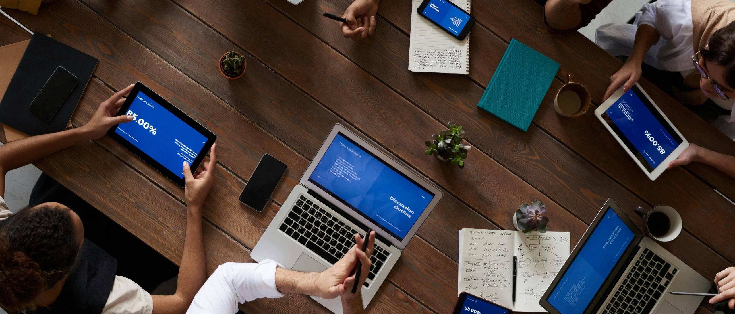 Vue du dessus d&rsquo;une &eacute;quipe utilisant ordinateurs portables, tablettes et smartphones lors d&rsquo;une r&eacute;union de travail.