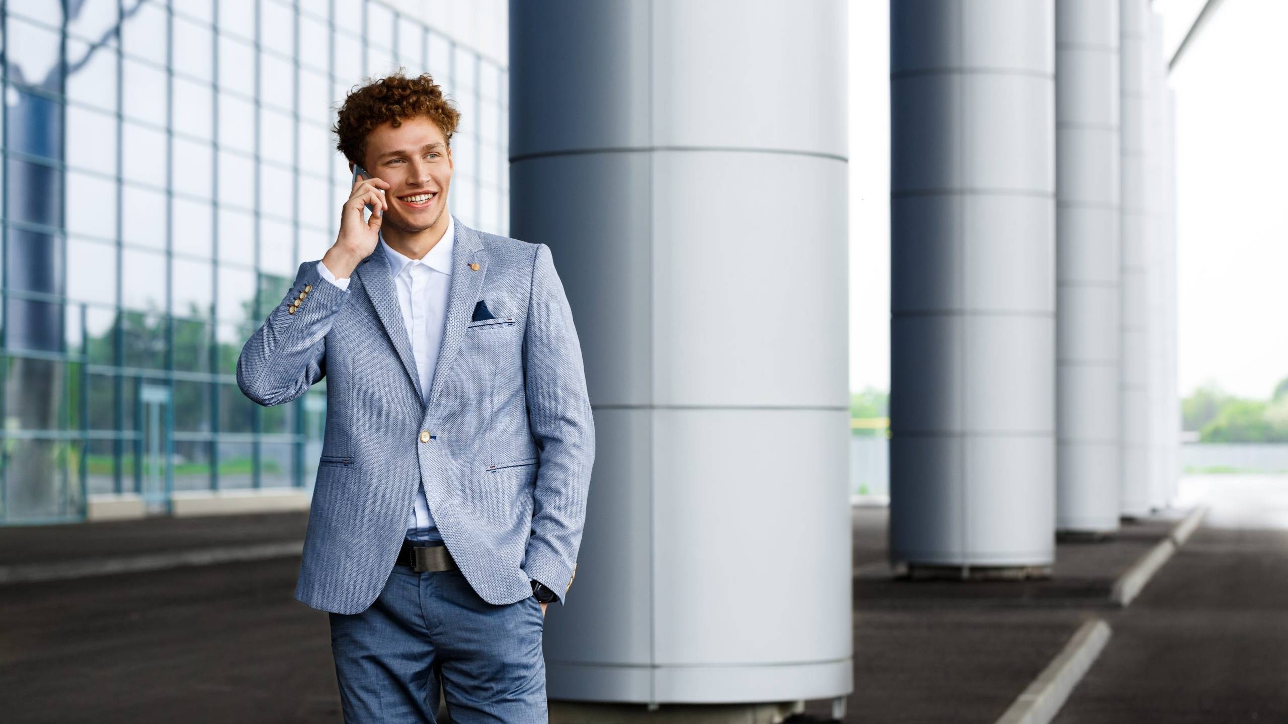 Jeune homme d&rsquo;affaires souriant aux cheveux roux parlant au t&eacute;l&eacute;phone.